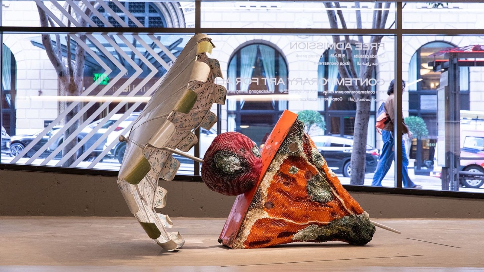 Escultura abstrata colorida que lembra uma pizza e um cupcake dentro do Instituto de Arte Contemporânea com grandes janelas mostrando a vista da rua do lado de fora. Imagem para ilustrar post sobre museus em San Francisco.