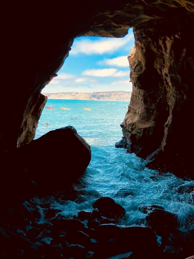 Foto de dentro de uma "caverna" dentro da praia de La Jolla. As pedras formam uma entrada e logo em frente está o resto do mar.