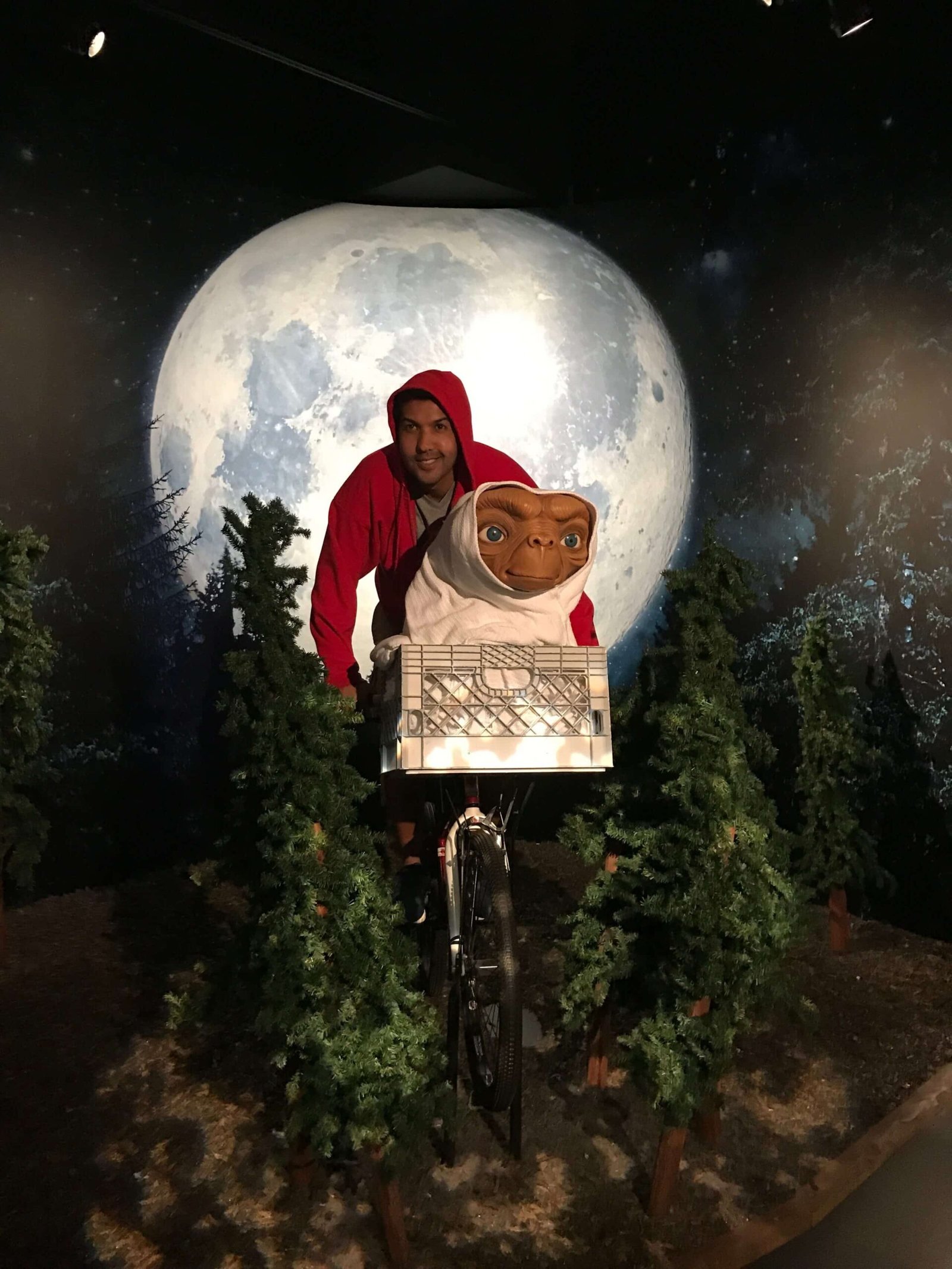 Um homem com moletom vermelho com capuz pilota a bicicleta do filme ET, com o ET na cestinha da bicicleta, recriando a cena icônica no Museu Madame Tussauds, uma das opções de o que fazer em Orlando.